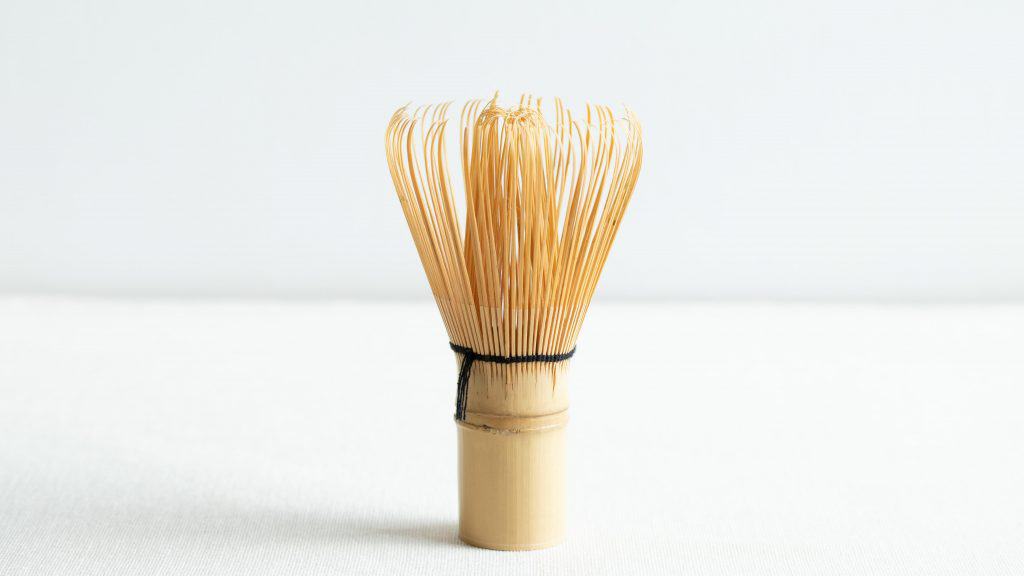 Bamboo matcha whisk standing upright on a white background.