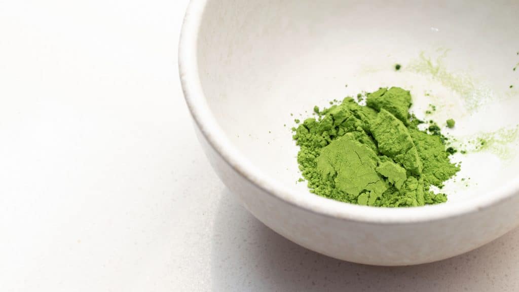 Bright green matcha powder in a white ceramic bowl